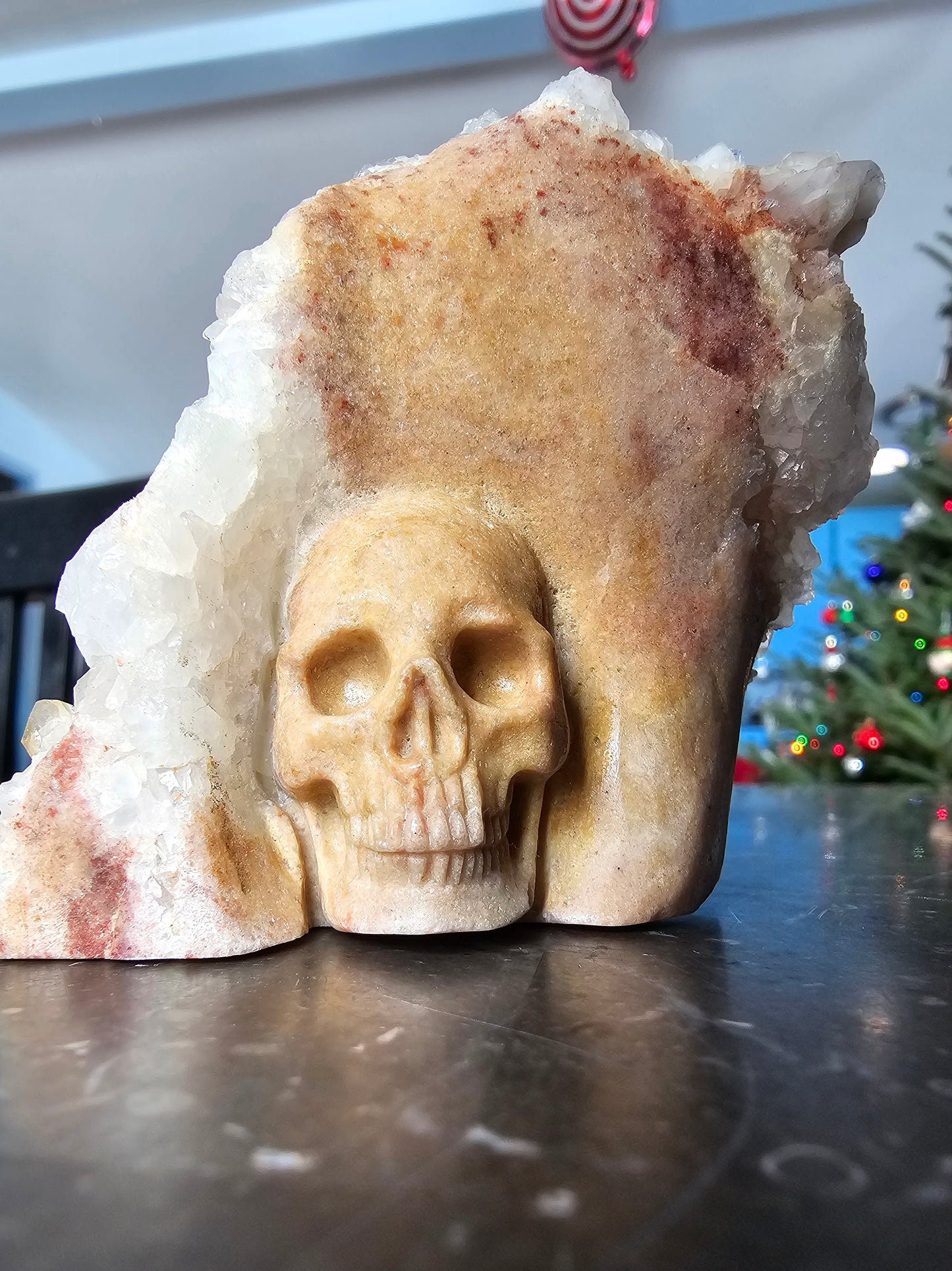 Clúster de cuarzo con calavera de sanador dorada tallada sobre matriz