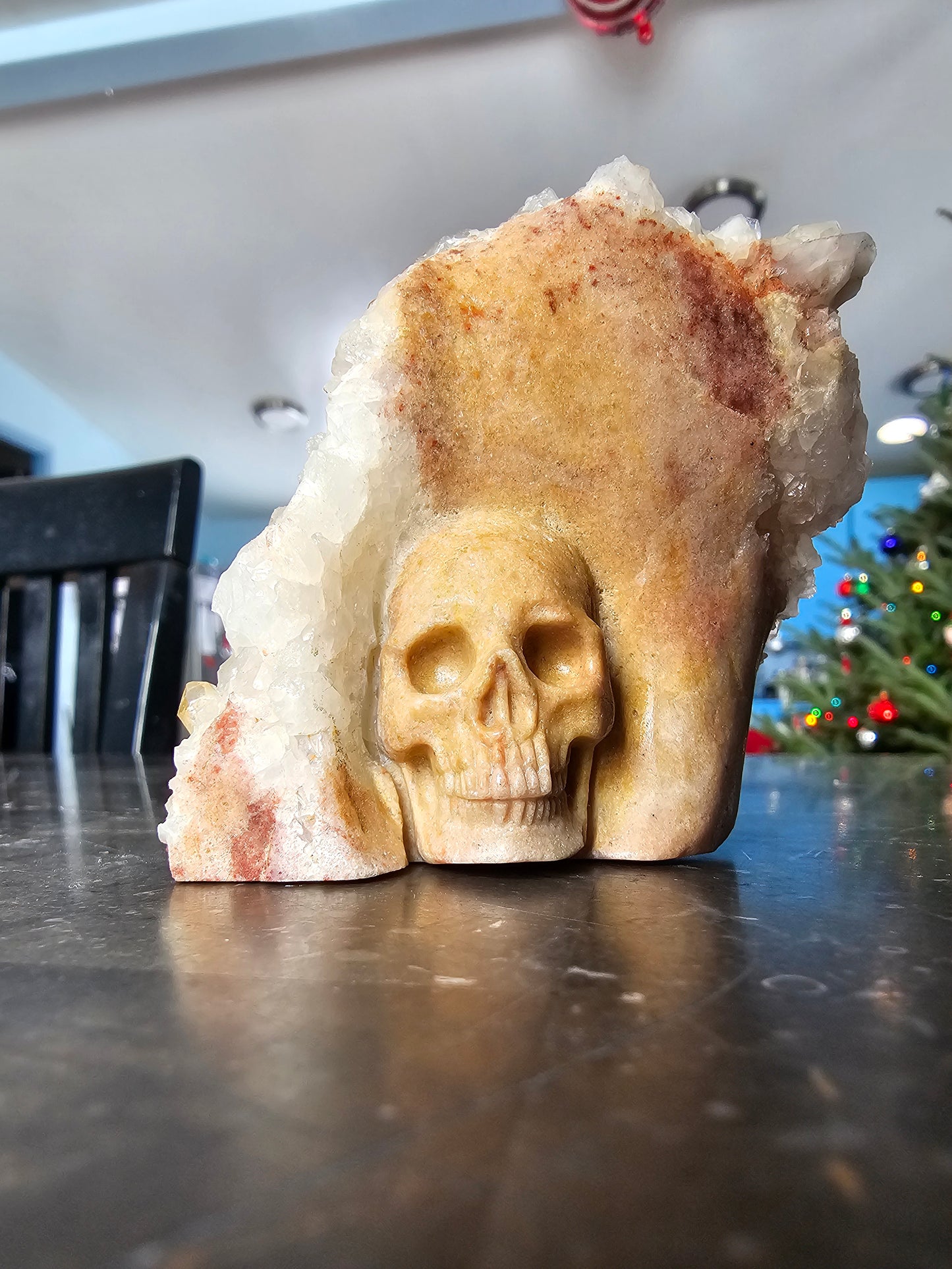 Clúster de cuarzo con calavera de sanador dorada tallada sobre matriz